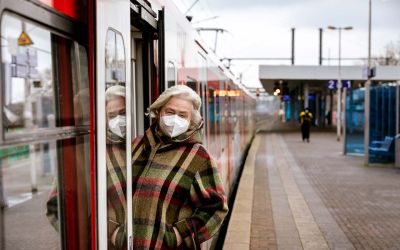 Frau mit FFP-Maske steigt in einen Zug