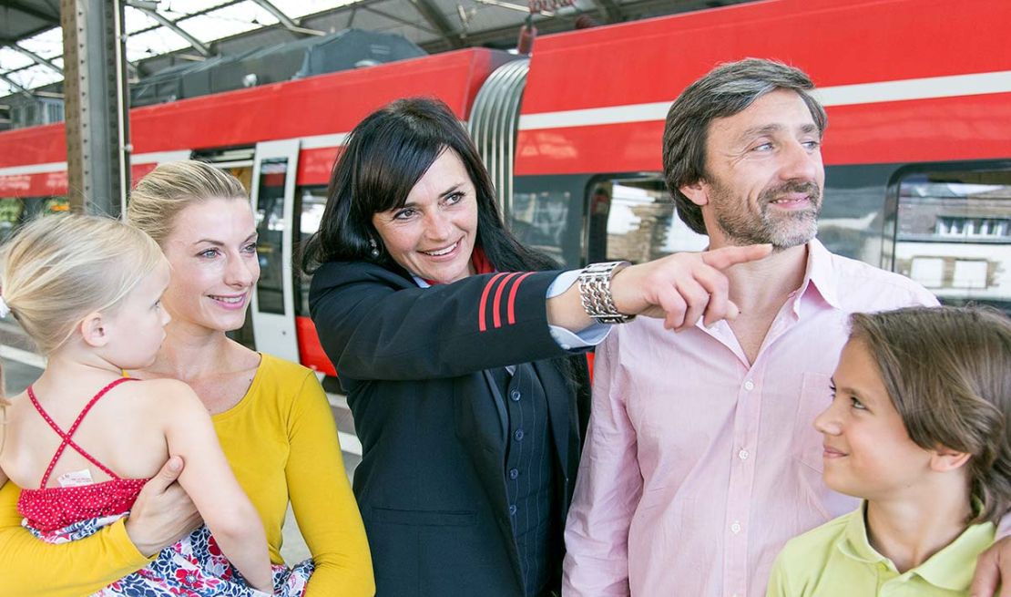 Eine Bahnmitarbeiterin weist einer Familie im Aachener Hauptbahnhof den Weg
