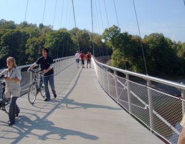 Radfahrer schieben ihre Fahrräder über eine Brücke