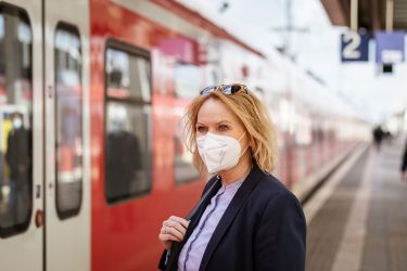 Frau mit FFP2-Maske am Bahnsteig