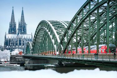 Ein Zug der DB färht über die winterliche Hohenzollernbrücke in Köln