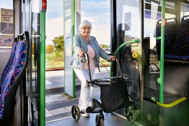Alte Dame steigt mit Rollator in den Bus